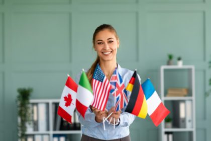 Happy female tutor showing bunch of diverse flags, recommending foreign language studying school